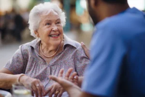 Senior woman smiling while talking with caregiver at an outdoor café in Philadelphia